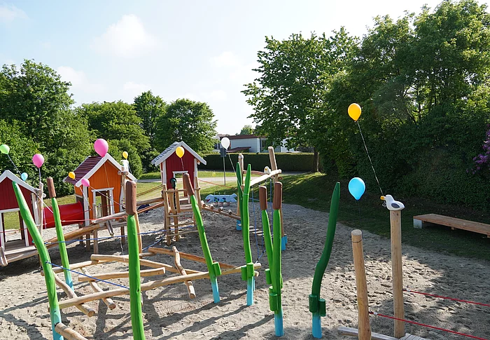 Spielplatz mit Spielhäusern, Balancier- und Kletterelementen.