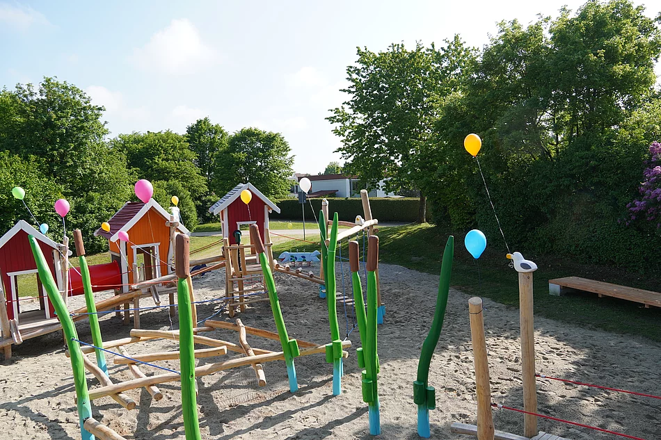 Spielplatz mit Spielhäusern, Balancier- und Kletterelementen.