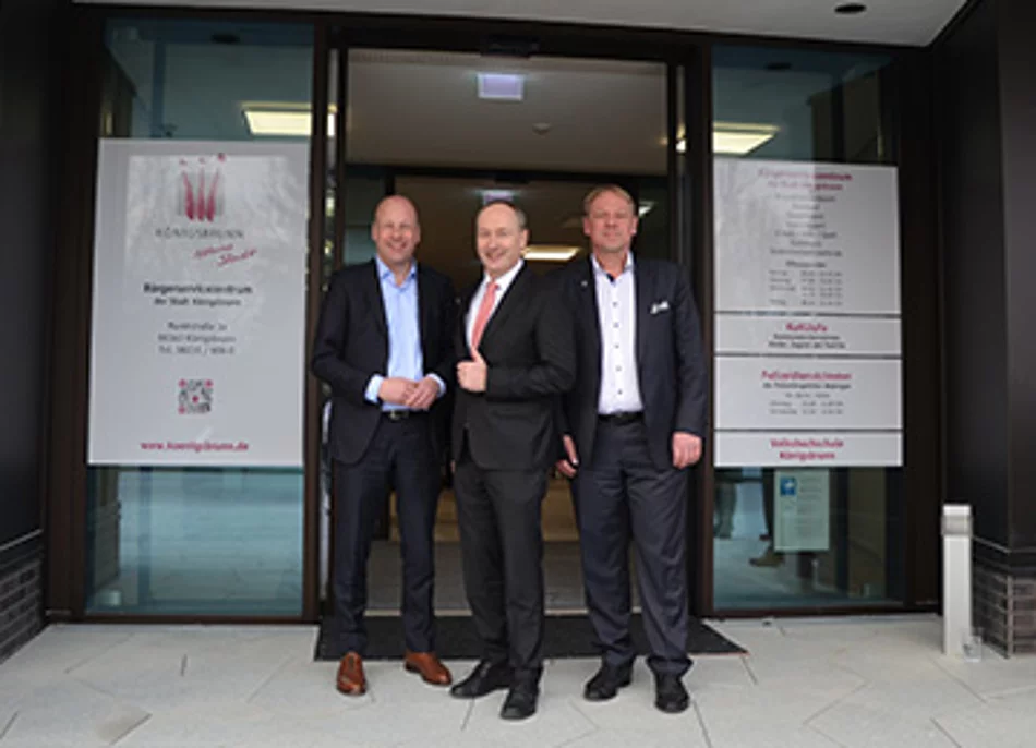Bürgermeister Franz Feigl, Landrat Martin Sailer und Günther Riebel  (GWG) stehen vor dem Eingangsbereich des neuen Königsbrunner Bürgerservicezentrums