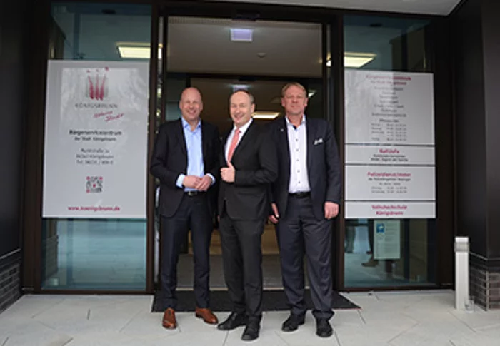 Bürgermeister Franz Feigl, Landrat Martin Sailer und Günther Riebel  (GWG) stehen vor dem Eingangsbereich des neuen Königsbrunner Bürgerservicezentrums