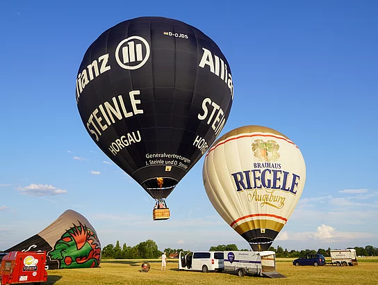 Heißluftballons starten auf einer Wiese.